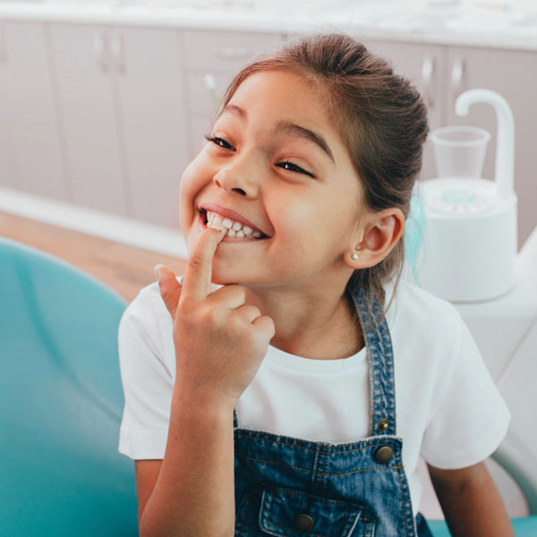 little girl pointing to her teeth