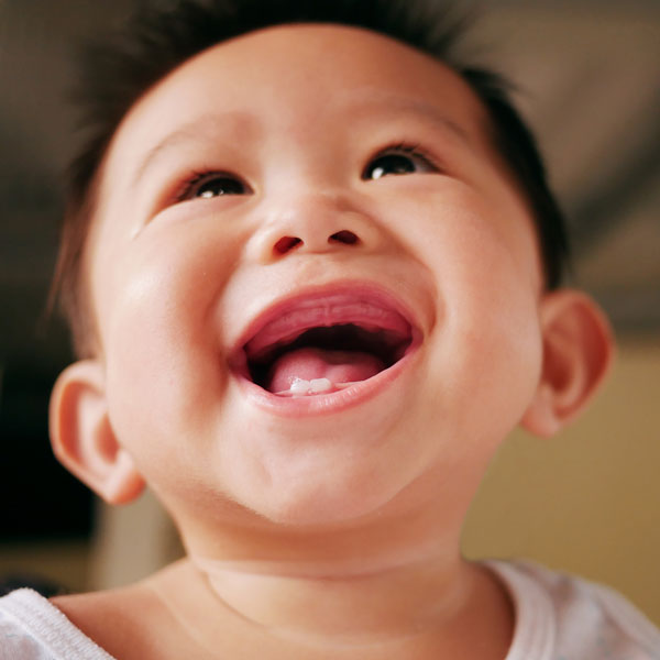 infant smiling with two bottom teeth