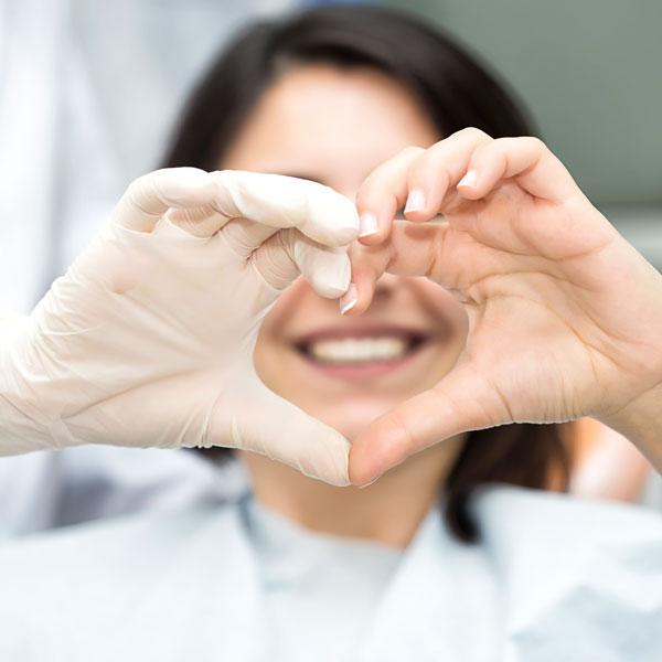 patient making a heart with dentists hands