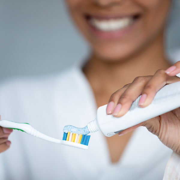 woman applying toothpaste to brush
